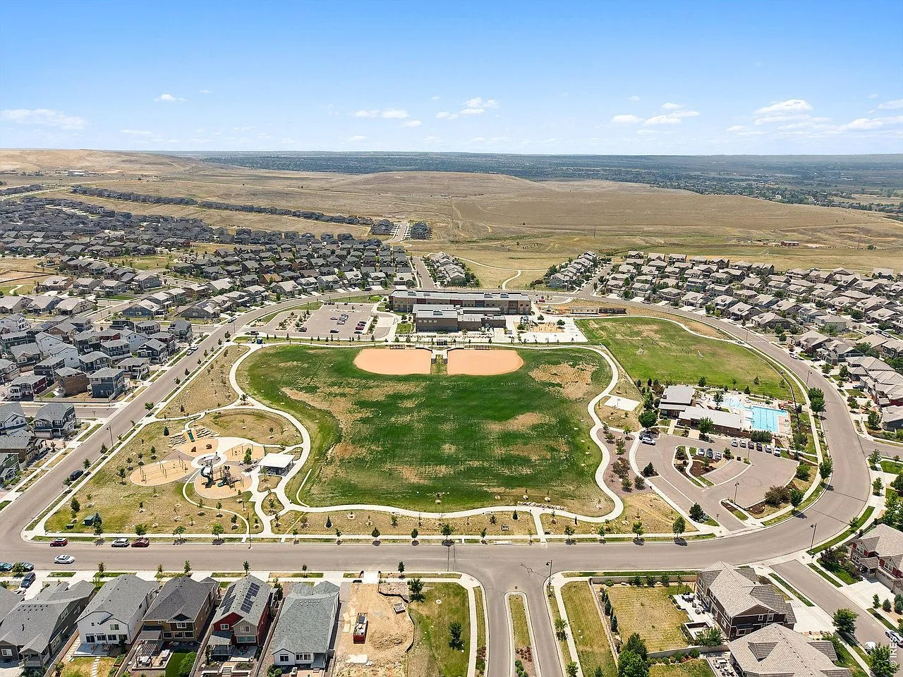 Aerial view of the Erie Highlands neighborhood, park, school and pool with the Front Range beyond