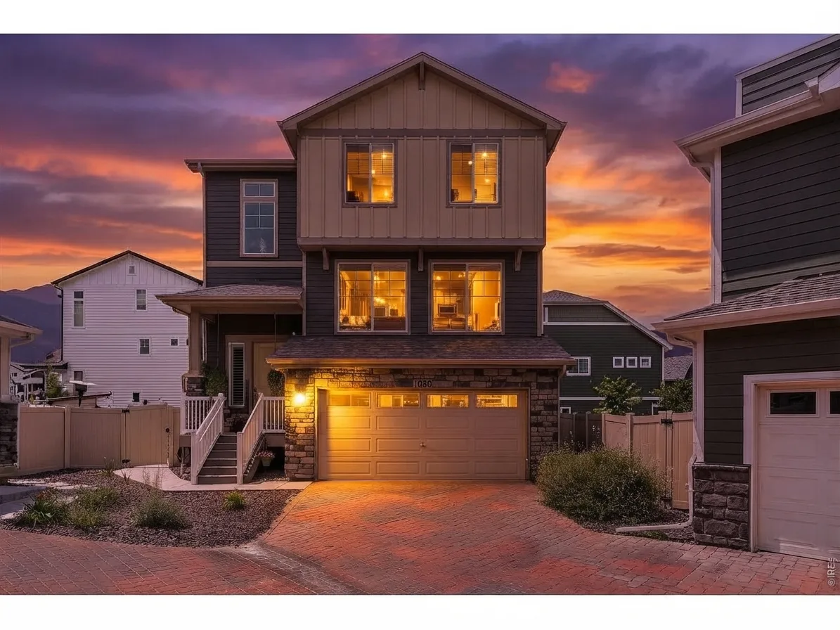 Front exterior of 1050 Highlands Dr glowing at twilight beneath a Colorado sunset